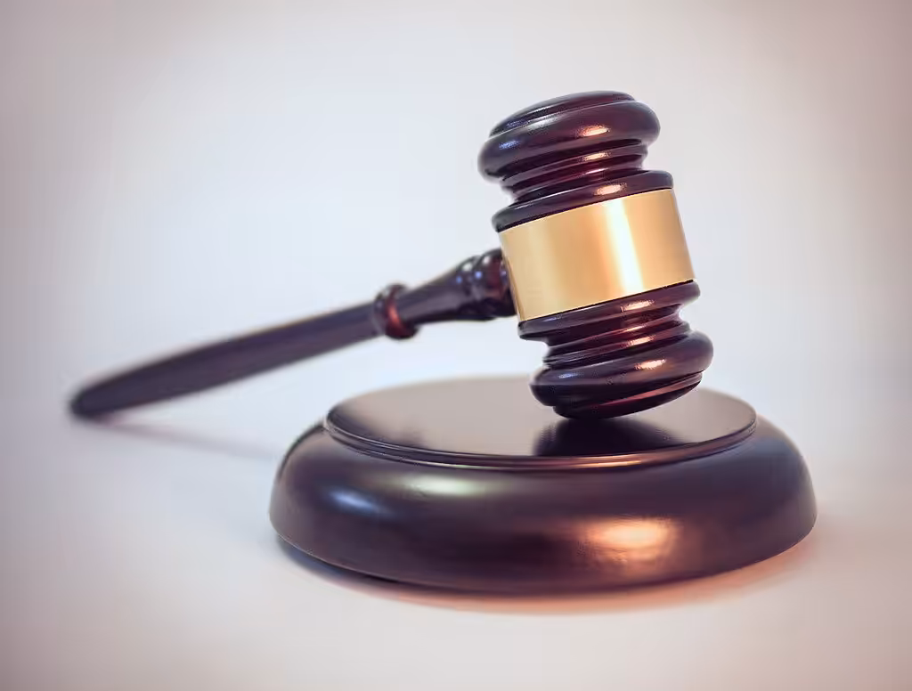 Wooden judge’s gavel resting on a desk, symbolizing legal enforcement and regulatory action.