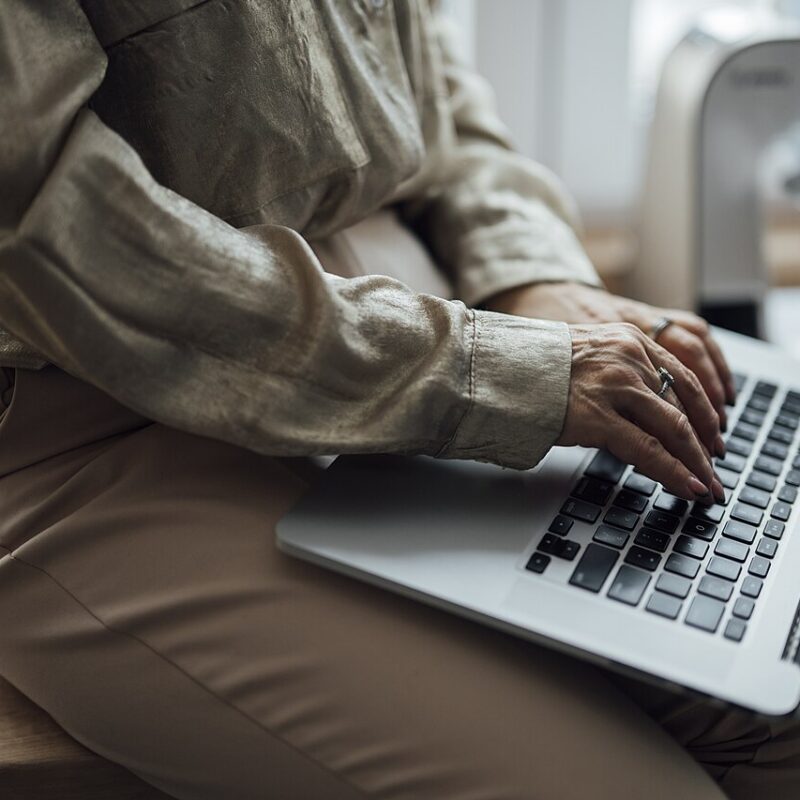 Woman using a laptop while sitting on a kitchen counter.