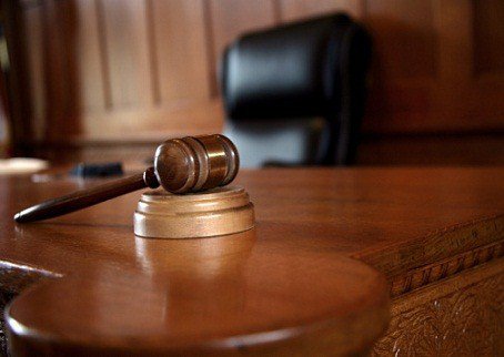 Wooden gavel resting on a sound block in a courtroom setting.