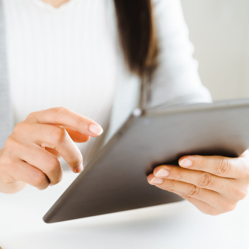 Close-up of a woman using a digital tablet in an office setting.