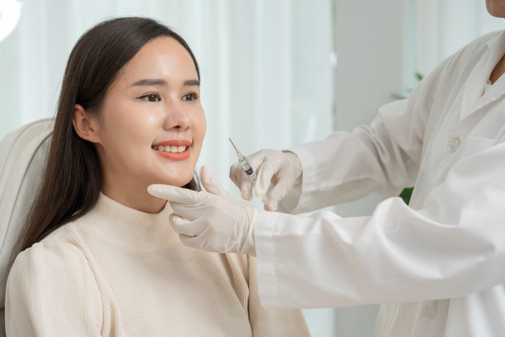 A woman receives a cosmetic facial injection in a clinical treatment setting.