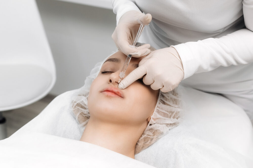 A gloved medical professional administers a hyaluronic acid filler injection into a woman's lips.